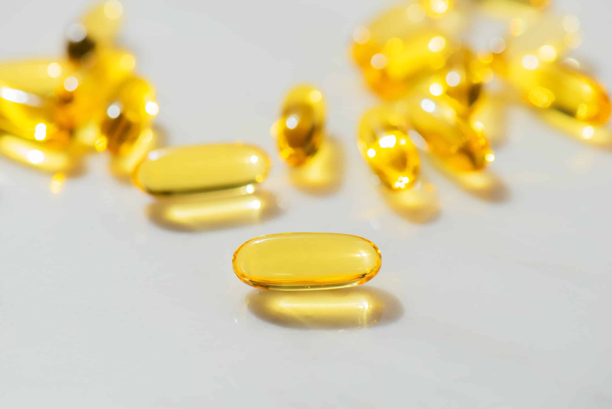 Close-up of fish oil scattered capsules with Omega-3 against white marble table ​high quality studio shot, Concept of healthy eating, disease prevention, and treatment diet. Taking supplements and vitamins. Dietary supplement