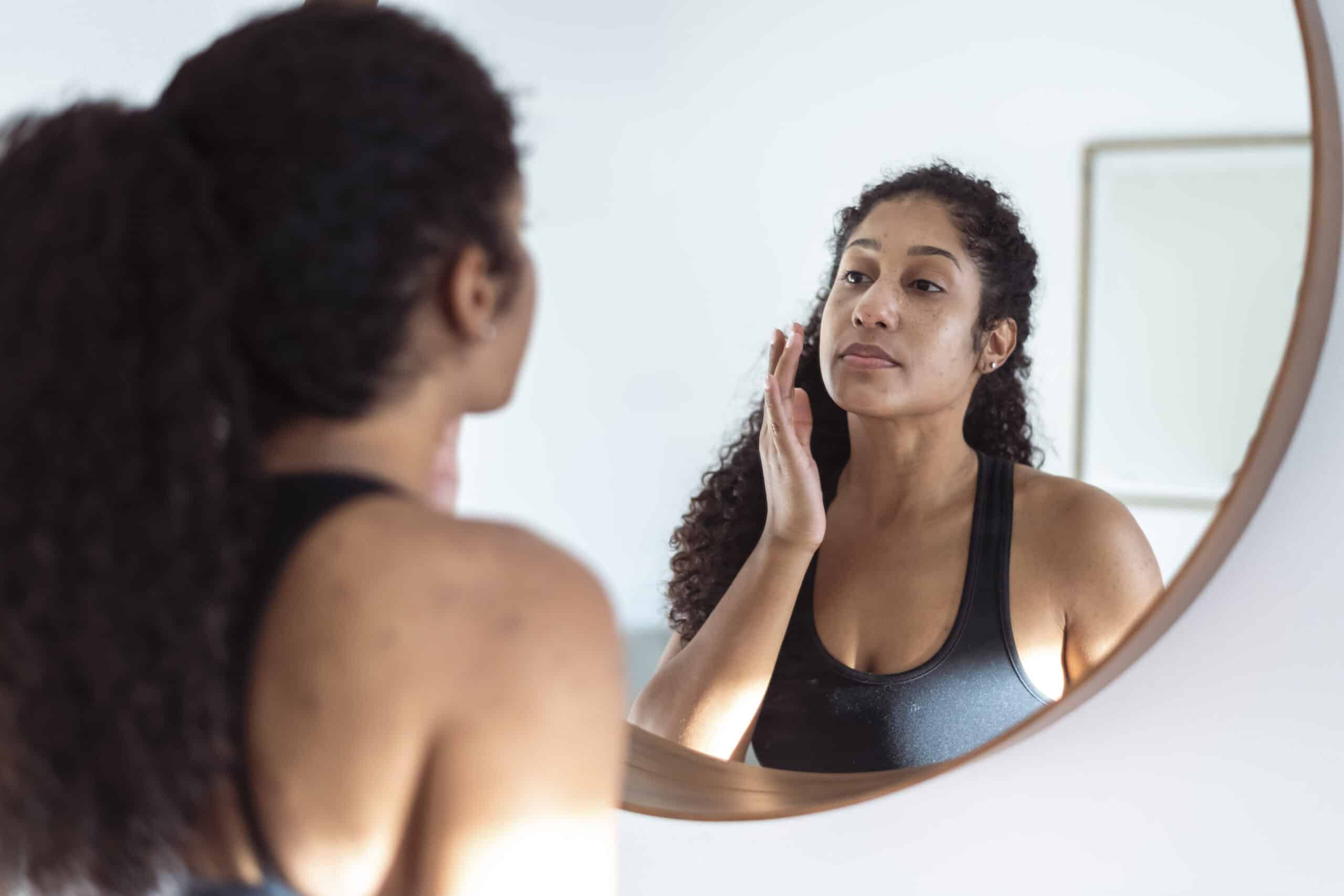 Ethnic woman applies suncream before going on a long run. She is wearing active wear.